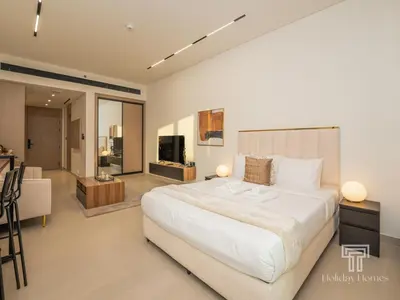 a bedroom with a large white bed and a living room at Brand New Luxe Studio Sauna, Gym&Pool With Access in Dubai