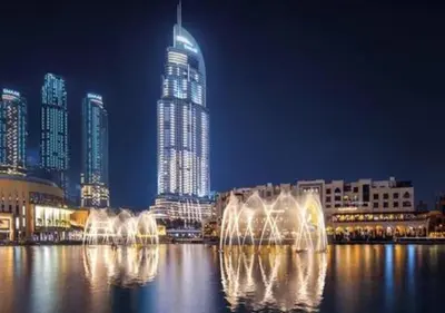 a large building with a fountain in the water at night at Dubai Mall Luxury 1Bed The Address in Dubai