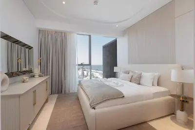 a white bedroom with a large bed and a window at Ultra Luxury 2BD Beachfront & Panoramic Sea Views in Dubai