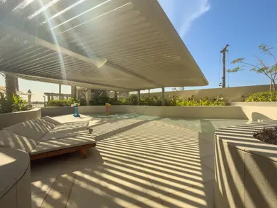 a patio with a bench under a white umbrella at Ultra Luxury 2BD Beachfront & Panoramic Sea Views in Dubai