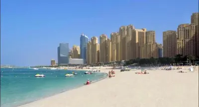 a beach with people in the water and buildings at Royal Marina Inn in Dubai