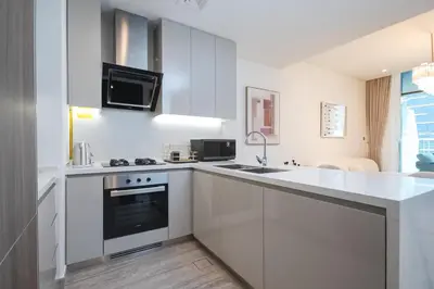 a white kitchen with a sink and a stove at Waterfront Luxe Haven Peninsula in Dubai