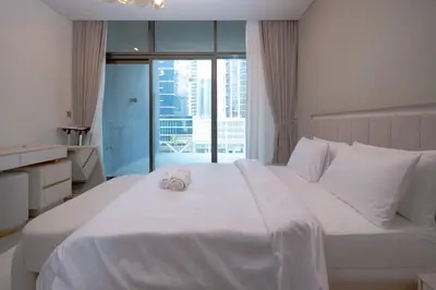 a white bed with a stuffed animal on top of it at Waterfront Luxe Haven Peninsula in Dubai
