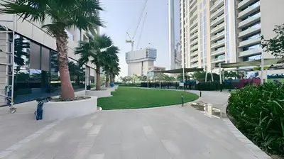 a park with palm trees in a city with buildings at Stunning 2 Bedroom Aykon City Tower C in Dubai