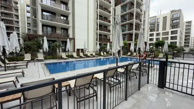a swimming pool with chairs and umbrellas and buildings at Luxury 1BR I Creek Beach I Pool & Beach in Dubai
