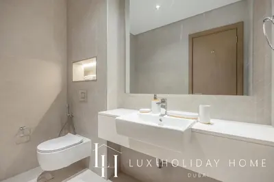 a bathroom with a sink and a toilet and a mirror at LUX The Burj Khalifa Lagoon View Suite 5 in Dubai