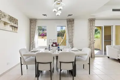 a dining room with a white table and chairs at Serene 2BR Villa, Minutes Drive to Miracle Garden and Dubai Butterfly Garden, Steps from Golf Course, Palmera 2, Arabian Ranches by Deluxe Holiday Homes in Dubai