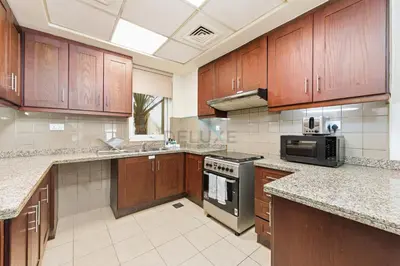 a large kitchen with wooden cabinets and appliances at Serene 2BR Villa, Minutes Drive to Miracle Garden and Dubai Butterfly Garden, Steps from Golf Course, Palmera 2, Arabian Ranches by Deluxe Holiday Homes in Dubai