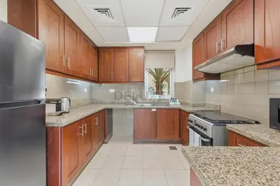 a large kitchen with wooden cabinets and stainless steel appliances at Serene 2BR Villa, Minutes Drive to Miracle Garden and Dubai Butterfly Garden, Steps from Golf Course, Palmera 2, Arabian Ranches by Deluxe Holiday Homes in Dubai