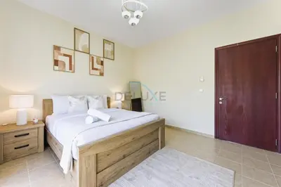 a bedroom with a large bed and a wooden door at Serene 2BR Villa, Minutes Drive to Miracle Garden and Dubai Butterfly Garden, Steps from Golf Course, Palmera 2, Arabian Ranches by Deluxe Holiday Homes in Dubai