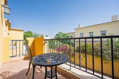a patio with a table and a chair on a balcony at Serene 2BR Villa, Minutes Drive to Miracle Garden and Dubai Butterfly Garden, Steps from Golf Course, Palmera 2, Arabian Ranches by Deluxe Holiday Homes in Dubai