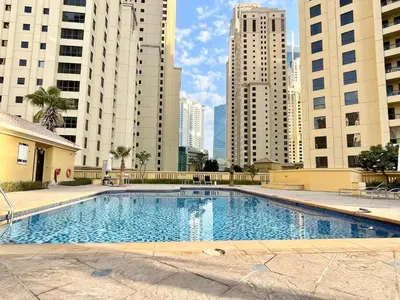 a large swimming pool in a city with tall buildings at Spacious 4BR in JBR Steps to Beach & Walk in Dubai