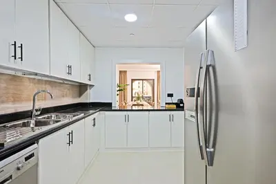 a kitchen with white cabinets and a stainless steel refrigerator at Spacious 4BR in JBR Steps to Beach & Walk in Dubai