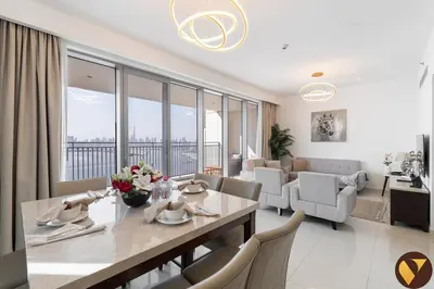 a dining room and living room with a table and chairs at Vogue Creek Harbour Icon Bay Waterfront Living Close to Downtown, Burj Khalifa and Dubai Mall, Three Bedroom Apartment with Large Balcony, Canal and Burj Khalifa View, Access to all Amenities in Dubai