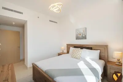 a bedroom with a large bed with white sheets at Vogue Creek Harbour Icon Bay Waterfront Living Close to Downtown, Burj Khalifa and Dubai Mall, Three Bedroom Apartment with Large Balcony, Canal and Burj Khalifa View, Access to all Amenities in Dubai
