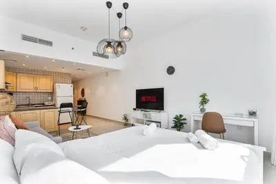 a living room with a white bed and a kitchen at Modern Cozy Studio Near Dubai Marina in Dubai