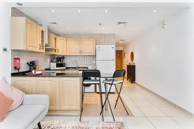 a kitchen with wooden cabinets and a white refrigerator at Modern Cozy Studio Near Dubai Marina in Dubai