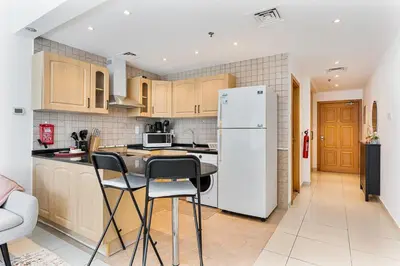 a kitchen with a white refrigerator and a table and chairs at Modern Cozy Studio Near Dubai Marina in Dubai
