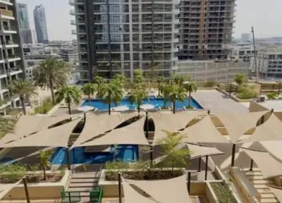 a pool with umbrellas and palm trees in a city at Luxury Living In JVC in Dubai