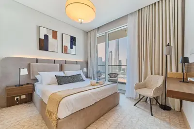 a bedroom with a bed and a desk and a window at Iconic 2BR Vida Dubai Mall with Direct Mall Access in Dubai