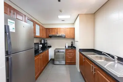 a kitchen with wooden cabinets and a stainless steel refrigerator at Modern 1 BHK Retreat in Lakeside JLT in Dubai