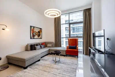 a living room with a couch and a tv at Golf Promenade 2-B, Damac Hills - 2BR Apartment - Allsopp & Allsopp in Dubai