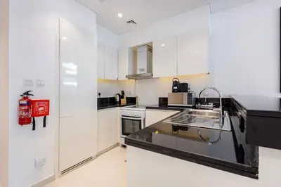 a kitchen with white cabinets and a sink at Golf Promenade 2-B, Damac Hills - 2BR Apartment - Allsopp & Allsopp in Dubai