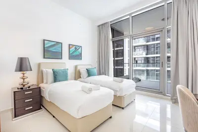 two beds in a room with a window at Golf Promenade 2-B, Damac Hills - 2BR Apartment - Allsopp & Allsopp in Dubai