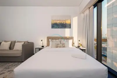 a white bedroom with a large bed and a couch at Studio Just Minutes Drive to Downtown Dubai Top Attractions, Close to Zabeel Stadium, O10 Building, Al Jaddaf by Deluxe Holiday Homes in Dubai