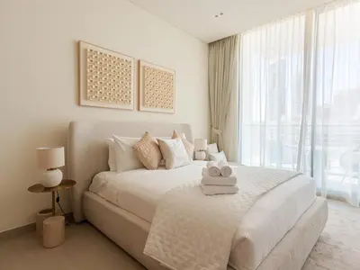 a white bedroom with a bed with two towels on it at WelHome - Perfect Cozy Studio with Pool, Gym & Balcony in Dubai
