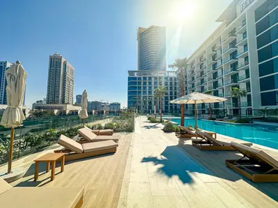 a pool with chairs and umbrellas next to a building at WelHome - Perfect Cozy Studio with Pool, Gym & Balcony in Dubai