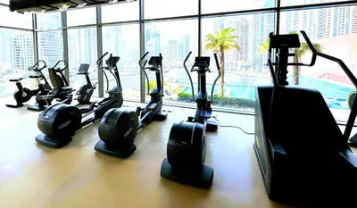 a row of exercise bikes in a gym with a window at Dubai Marina Luxury 1 BDR Holiday Apartment - Dubai Marina Walk in Dubai