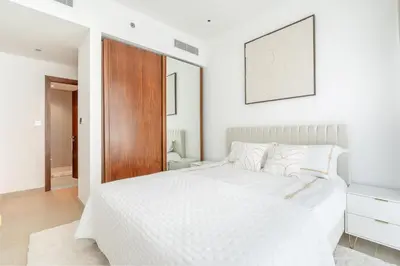 a white bedroom with a white bed and a wooden door at Dubai Marina Luxury 1 BDR Holiday Apartment - Dubai Marina Walk in Dubai