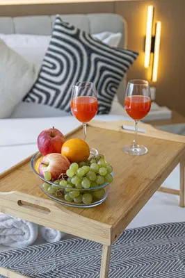 a table with a bowl of fruit and two wine glasses at Livin' Holidays - Studio - Azizi Elegant Studio in Dubai
