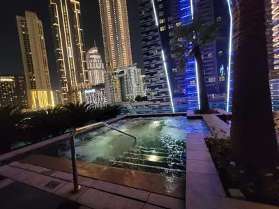 a swimming pool in the middle of a city at night at Downtown Dubai Burj Khalifa View 2 BHK Dubai Mall in Dubai