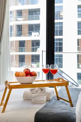 a table with a bowl of fruit and two glasses of wine at Livin' Holidays - Studio - Azizi Lovely Studio in Dubai