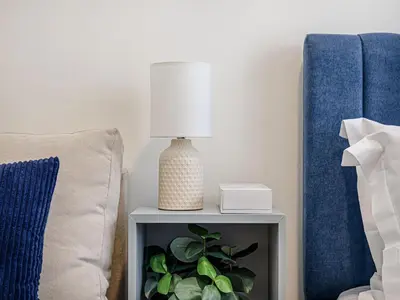 a table with a lamp on it next to a bed at Livin' Holidays - Studio - Azizi Lovely Studio in Dubai