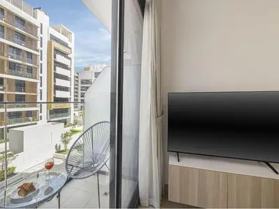 a living room with a flat screen tv and a window at Livin' Holidays - Studio - Azizi Lovely Studio in Dubai