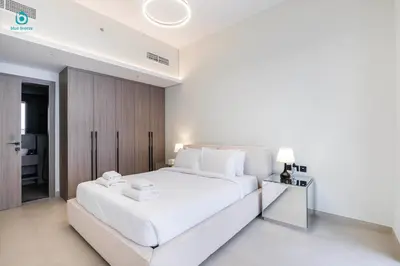 a white bedroom with a large white bed with two towels at Blue Breeze - Stylish 1 BR in JVC Al Serh Residence in Dubai