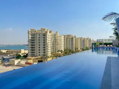 a large swimming pool with a view of a city at Luxe Island Retreat 1BR in Palm-14 in Dubai