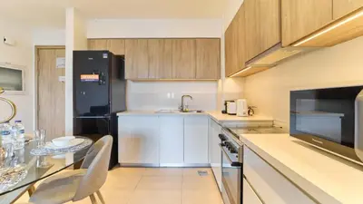a kitchen with a table and a black refrigerator at 1BR Dubai Hills Executive Residence Stylish Stay in Dubai