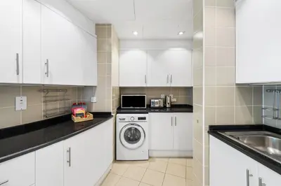 a kitchen with white cabinets and a washer and dryer at Ultra-Luxury Penthouse Private Pool & Yacht Views in Dubai