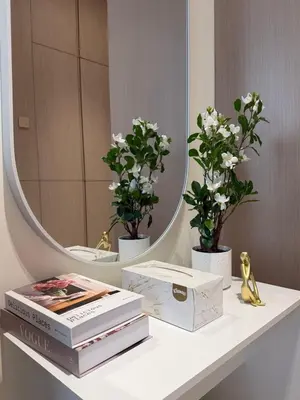 a table with books and flowers and a mirror at Stylish Studio JVC I Epic Amenities I Near Mall in Dubai