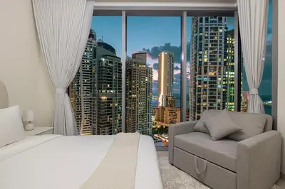 a bedroom with a bed and a chair and a large window at Marina High-Floor Premium Luxury Stay at LIV Marina for up to 9 Guests with Marina Views and Exceptional Amenities in Dubai