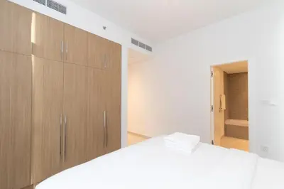 a bedroom with a white bed and wooden cabinets at 1 BDR Ellington House, Dubai Hills in Dubai