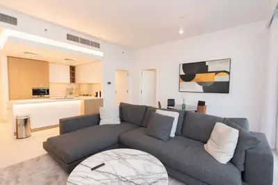 a living room with a gray couch and a kitchen at Boutique 2BDR Ellington House, Dubai Hills in Dubai