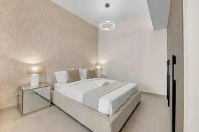a white bedroom with a large bed and a table at Waves - Modern Comfort in JVC - Elegant 1BR Stay in Dubai