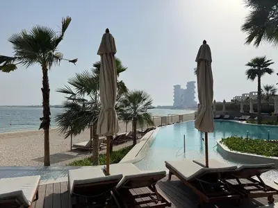 a swimming pool with chairs and umbrellas next to the beach at 1 BR apartment in Ellington Beach House in Dubai