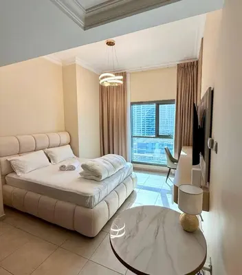 a living room with a bed and a table and a tv at Dubai Marina 5 min to the beach in Dubai