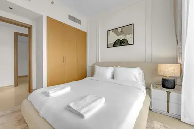 a bedroom with a large white bed with a towel on it at Neat 3BR Habour Views with Balcony-Burj Khalifa View, Pool, Gym and Modern Facilities in Dubai